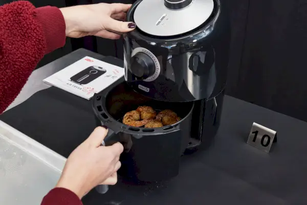 Une personne sortant de la nourriture d’une friteuse à air compacte Dash