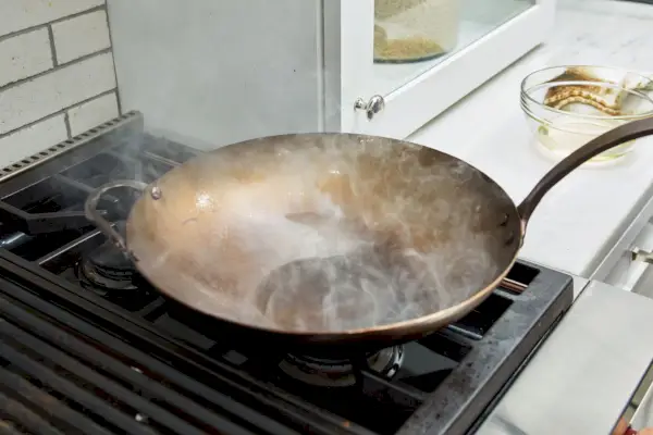 Zbliżenie na podgrzewany ręcznie kuty wok ze stali węglowej Smithey Ironware Co. na kuchence