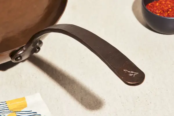 Zbliżenie na uchwyt Smithey Ironware Co., ręcznie kuty wok ze stali węglowej