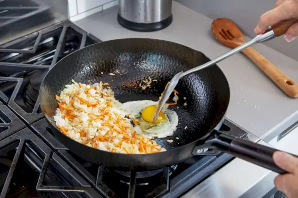 Osoba gotująca jajka i placki ziemniaczane w woku ze stali węglowej Souped Up Recipes