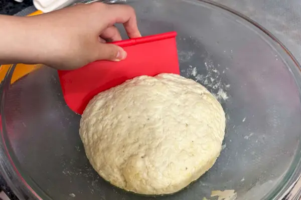 Une personne utilise le grattoir d'établi 3 en 1 Chefn Pastrio pour façonner la pâte