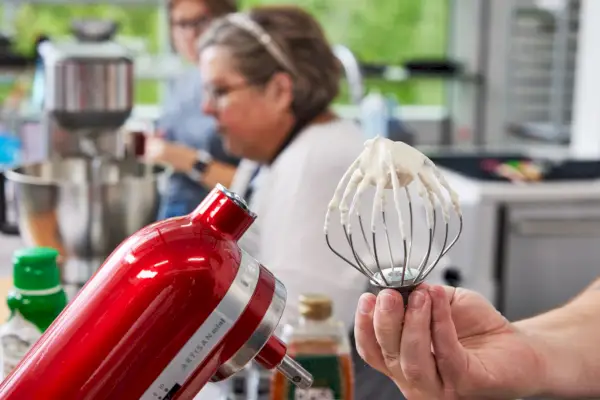 אדם אוחז בחיבור למיקסר מקצף סטנד 3.5 קוורט KitchenAid Artisan Mini מכוסה בבצק