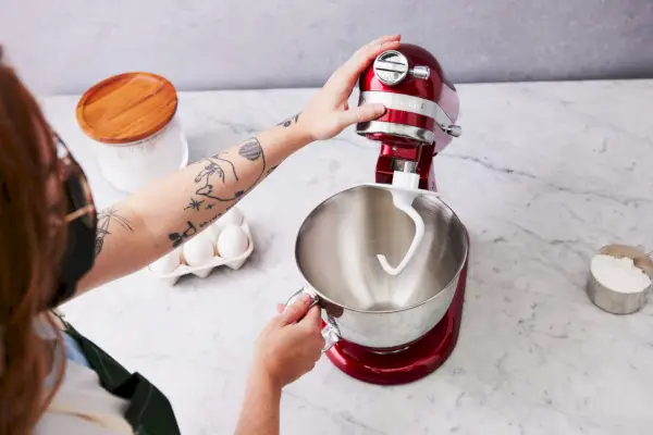 חלקו העליון של מיקסר עמדת ה-Breville Bakery Chef הוטה מתוך קערת המיקסר כשהבצק יורד מחיבור וו הבצק