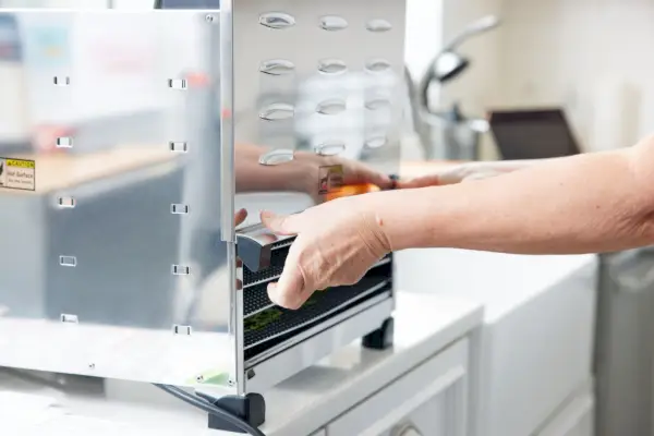 Personne retirant le plateau du déshydrateur alimentaire