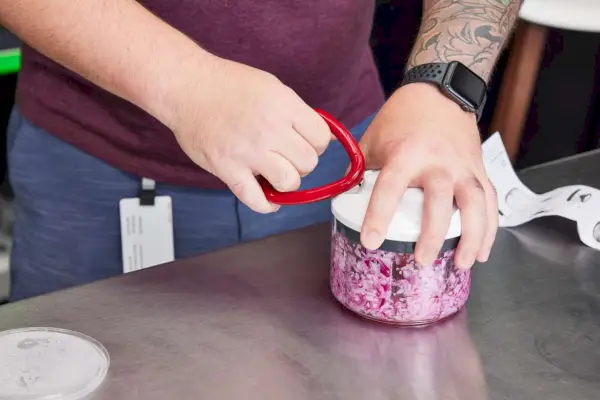 Osoba, která používá ruční kuchyňský robot Zyliss Easy Pull k sekání červené cibule