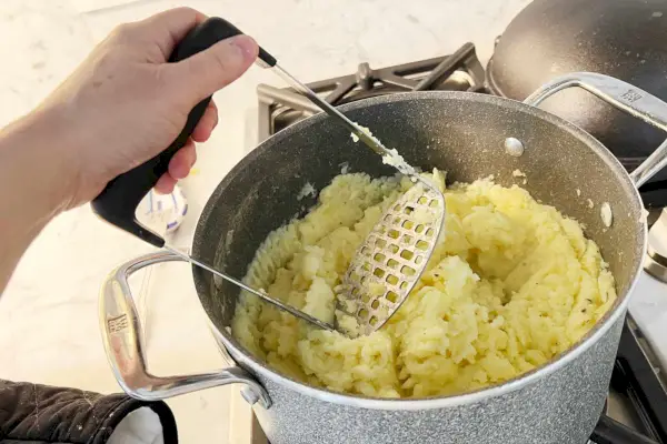 Espremedor de batatas em uma tigela de batatas