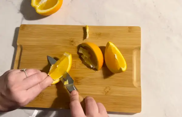 도마 위의 오렌지 껍질을 벗기기 위해 Made In Paring Knife를 사용하는 사람
