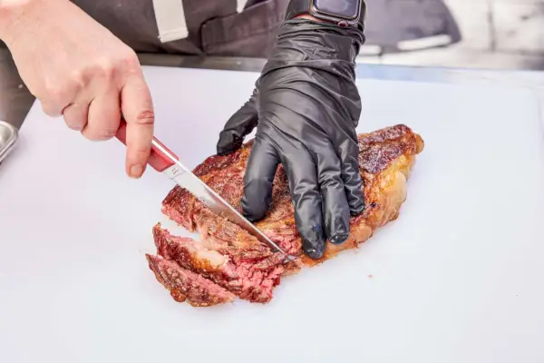 Osoba kroi mięso ugotowane w 18-calowym cyfrowym grillu węglowym i wędzarni Kamado Joe Konneted Joe