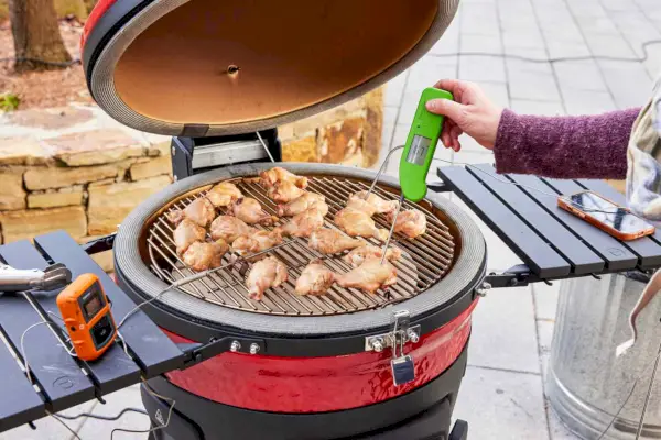 Osoba sprawdza temperaturę kurczaka ugotowanego w 18-calowym cyfrowym grillu i wędzarni Kamado Joe Konneted Joe