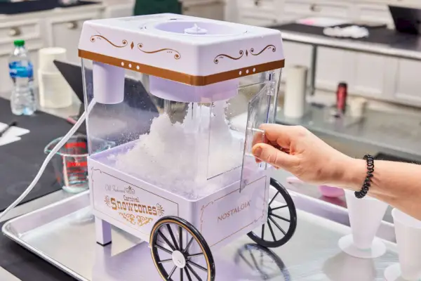 Nostalgia Vintage Schneekegel-Maker für die Arbeitsplatte (SCM525WH), gefüllt mit Schneekegeln und geraspelten Eisleckereien