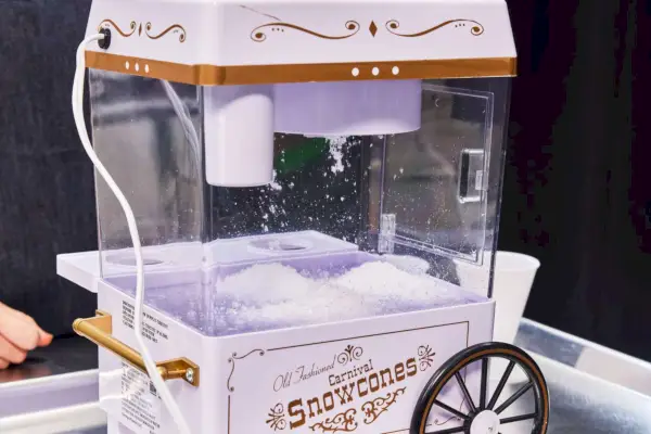 Nostalgia Vintage Schneekegelbereiter für die Arbeitsplatte (SCM525WH), abgebildet mit Schneestücken
