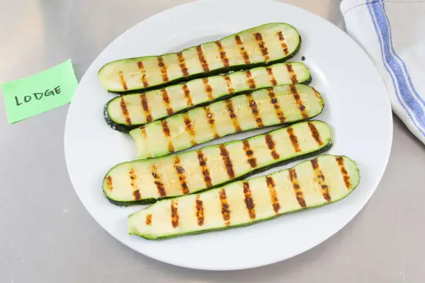 In Scheiben geschnittene gegrillte Zucchini auf einer Glasplatte.