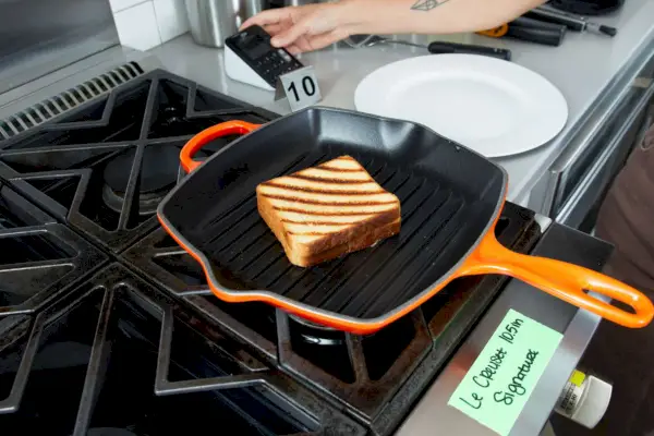 Eine Person kocht einen gegrillten Käse mit der Le Creuset Square Skillet Grill Pan.