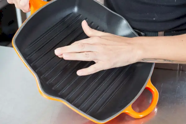 Eine Person berührt die Grillrippen der Le Creuset Square Skillet Grillpfanne.