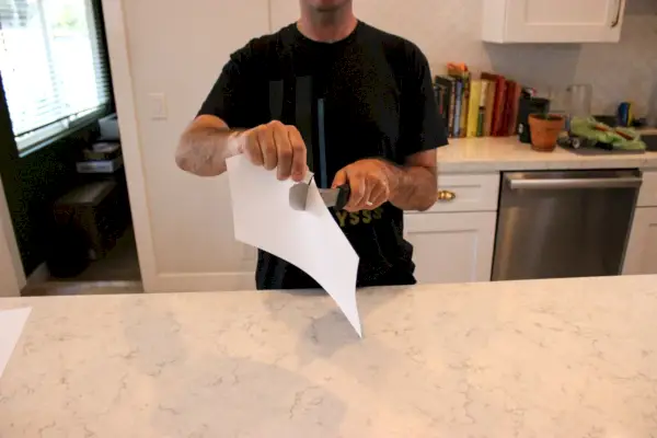 Personne utilisant un couteau de boucher professionnel Zwilling Twin Master de 8 pouces pour couper du papier