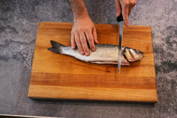 Une personne filet un poisson à l'aide du couteau à filet flexible Victorinox de 8 pouces