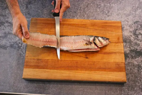 Une personne utilise le couteau à filet flexible Victorinox de 8 pouces pour fileter un poisson