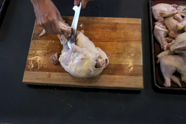Couteau de boucher classique Wusthof dépeçant du poulet sur une planche à découper