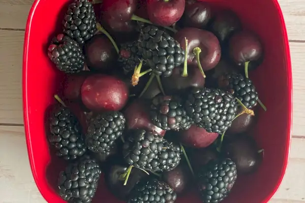 Ciliegie e frutti di bosco del mercato di Misfit seduti in una ciotola rossa sul tavolo