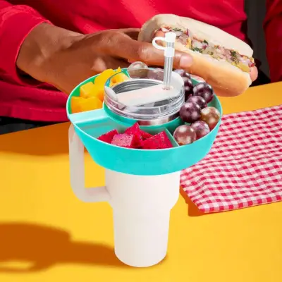 Snackschüssel-Zubehör auf einem Stanley-Becher platziert, mit einer Person, die einen Hotdog im Hintergrund hält