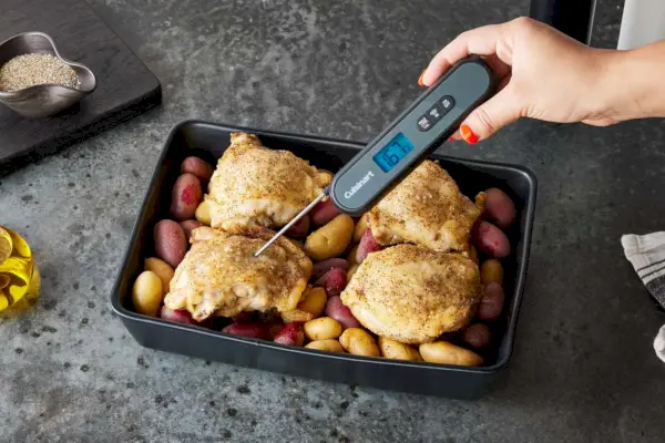 Person, die das digitale Fleischthermometer von Kizen verwendet, um die Temperatur von Huhn in einem Ofen zu überprüfen