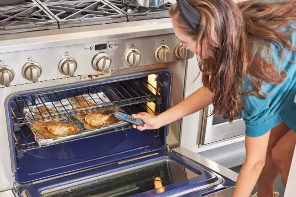 Person, die das Infrarot- und klappbare Grillthermometer Cuisinart CSG-200 verwendet, um die Temperatur des Hähnchens im Ofen zu überprüfen