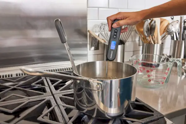 Person, die das Infrarot- und klappbare Grillthermometer Cuisinart CSG-200 verwendet, um die Temperatur des kochenden Wassers auf dem Herd zu überprüfen