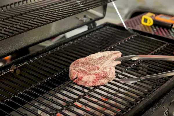 אדם צולה בשר על גריל פחמים קלאסי של Char-Griller