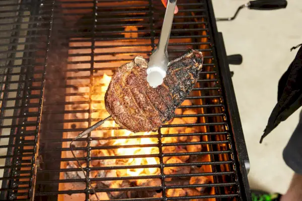 אדם צולה בשר באמצעות גריל פחמים קלאסי Char-Griller