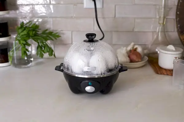 Dash Rapid Egg Cooker sedí na kuchyňské lince a vaří celá vejce