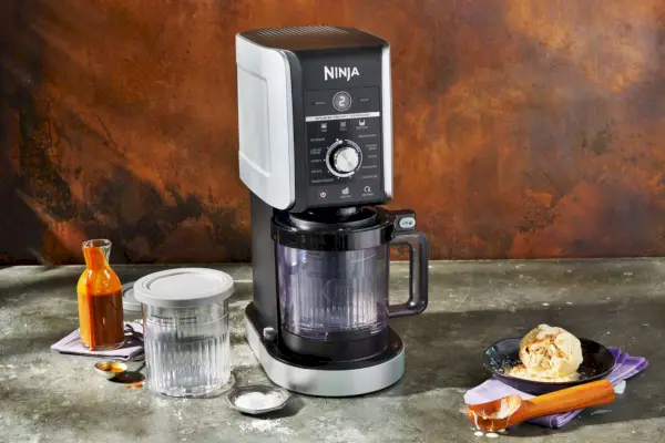 Výrobník zmrzliny XL Ninja Creami Deluxe 11 v 1 na sivom mramorovanom povrchu vedľa misky zmrzliny