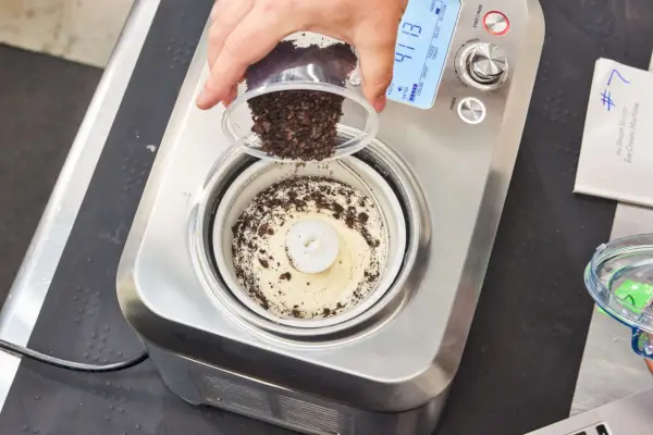 Ručné posypanie kúskov čokolády do zmrzliny vo vnútri Breville The Smart Scoop Ice Cream Maker