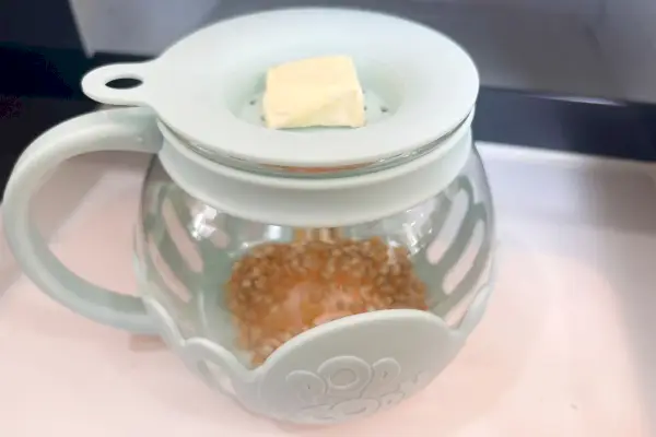 חתיכת חמאה יושבת על גבי הפופקורן של Ecolution Micro-Pop Microwave Popcorn.