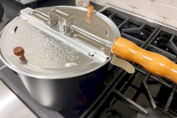 מכונת הפופקורן המקורית של כיריים Whirley Pop של Franklin יושבת על גבי כיריים.