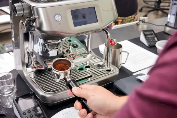 Uma pessoa segurando o porta-filtro do Breville The Barista Touch Impress (BES881BSS1BNA1)
