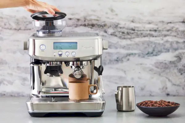 uma pessoa abrindo uma máquina de café expresso Breville The Barista Express