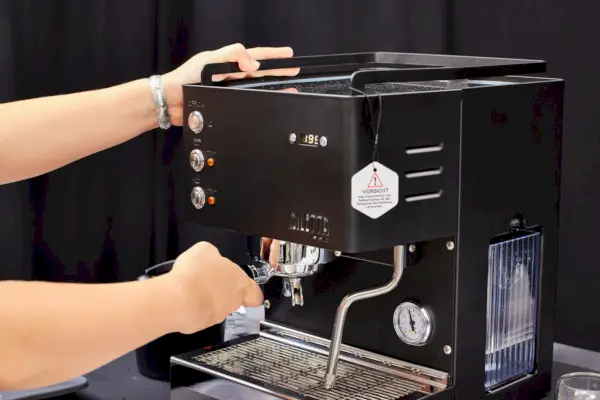 Uma pessoa ajustando o porta-filtro da máquina de café expresso Diletta Mio
