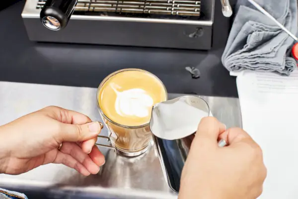 Uma pessoa preparando um café com leite na máquina de café expresso Diletta Mio