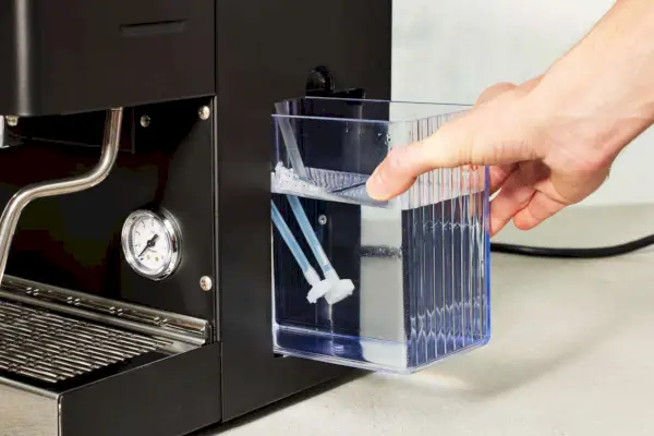 Uma pessoa segurando o recipiente de água da máquina de café expresso Diletta Mio