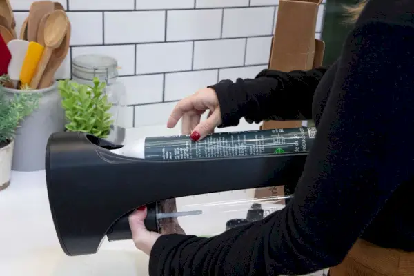 Osoba upraví nádrž na CO2 v zariadení na výrobu perlivej vody a sódy Drinkmate OmniFizz