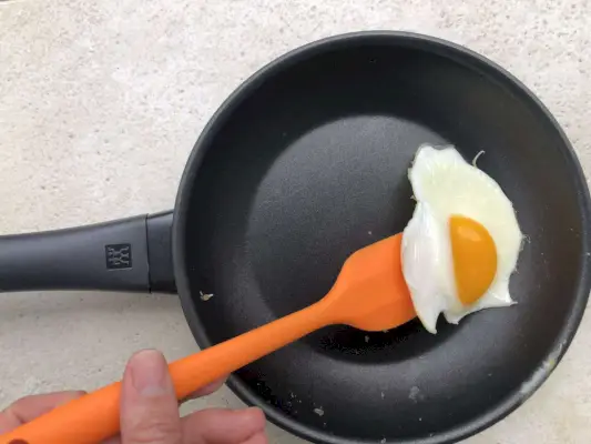 Person hebt ein Spiegelei aus der Zwilling Madura Plus 8 Zoll Antihaft-Bratpfanne