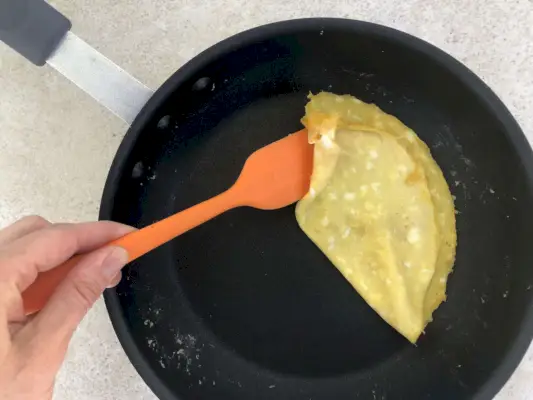 Person hebt Omelett aus der 8,25-Zoll-Pfanne von Nordic Ware Restaurant Cookware