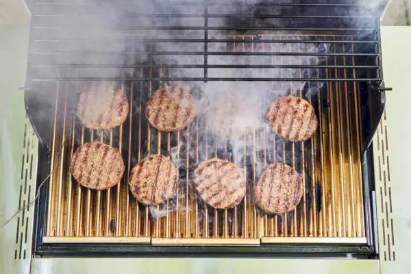 Hambúrgueres são cozidos na churrasqueira a gás propano líquido Sabre Select de aço inoxidável com 3 queimadores