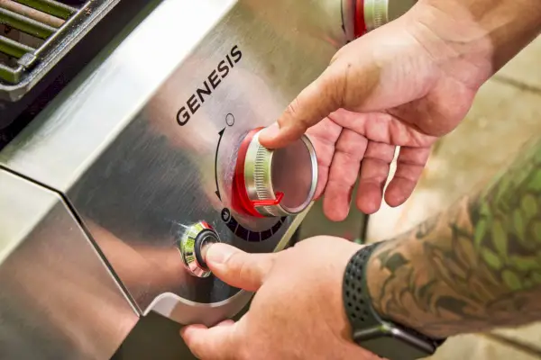 Uma pessoa liga a churrasqueira a gás propano líquido Weber Genesis E-325