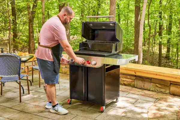 Uma pessoa ajusta a temperatura na churrasqueira a gás propano líquido Weber Genesis E-325