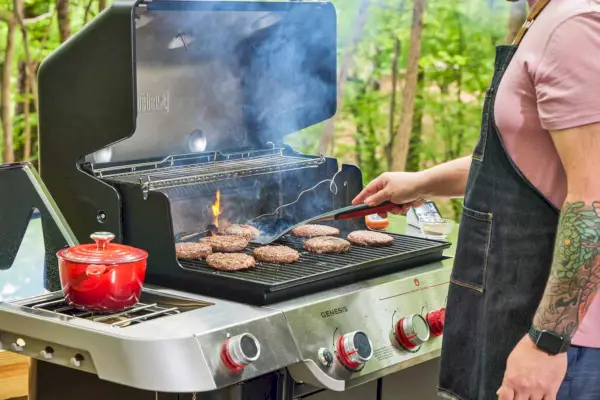 Uma pessoa cozinha carne na churrasqueira a gás Weber Genesis E-335