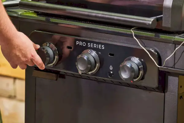 Uma pessoa ajusta a temperatura na churrasqueira a gás Char-Broil 463365124 Pro Series 3 Burner