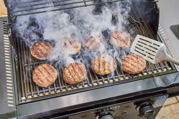 Uma pessoa cozinha carne na churrasqueira a gás Char-Broil 463365124 Pro Series 3 Burner
