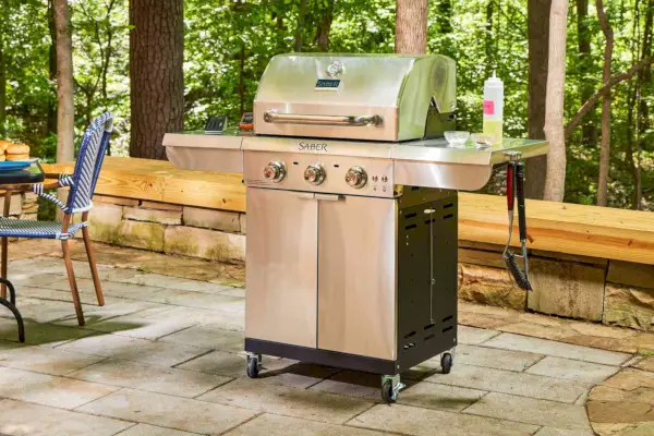 A churrasqueira a gás propano líquido Sabre Select inoxidável com 3 queimadores em um pátio