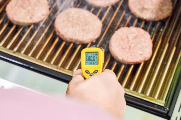 Uma pessoa verifica a temperatura da churrasqueira a gás propano líquido Sabre Select inoxidável com 3 queimadores
